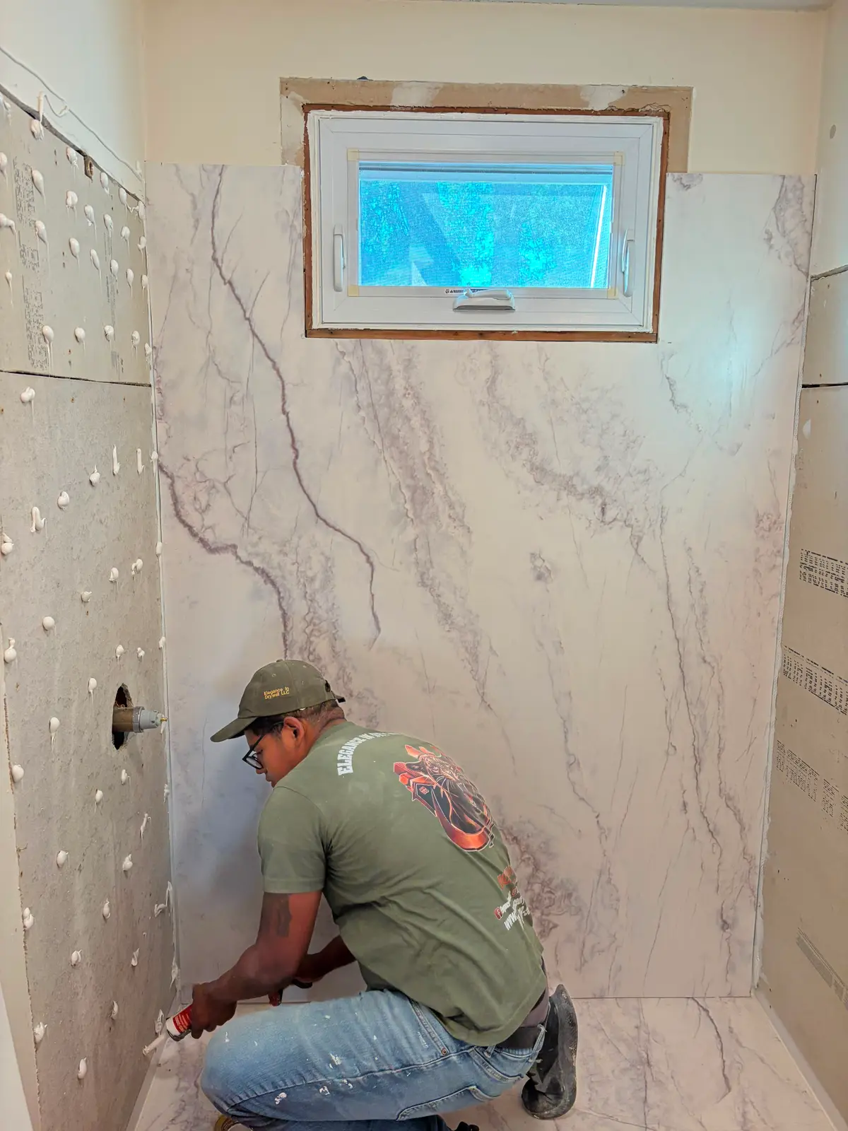 A C&C Multiservices technician installing marble-look shower wall panels during a Connecticut bathroom renovation