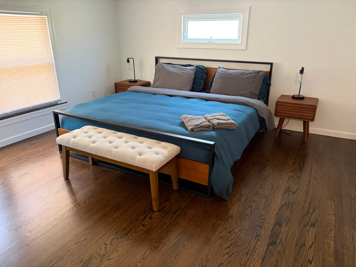 Newly remodeled master bedroom with hardwood flooring and blue bedding by C&C Multiservices in Connecticut
