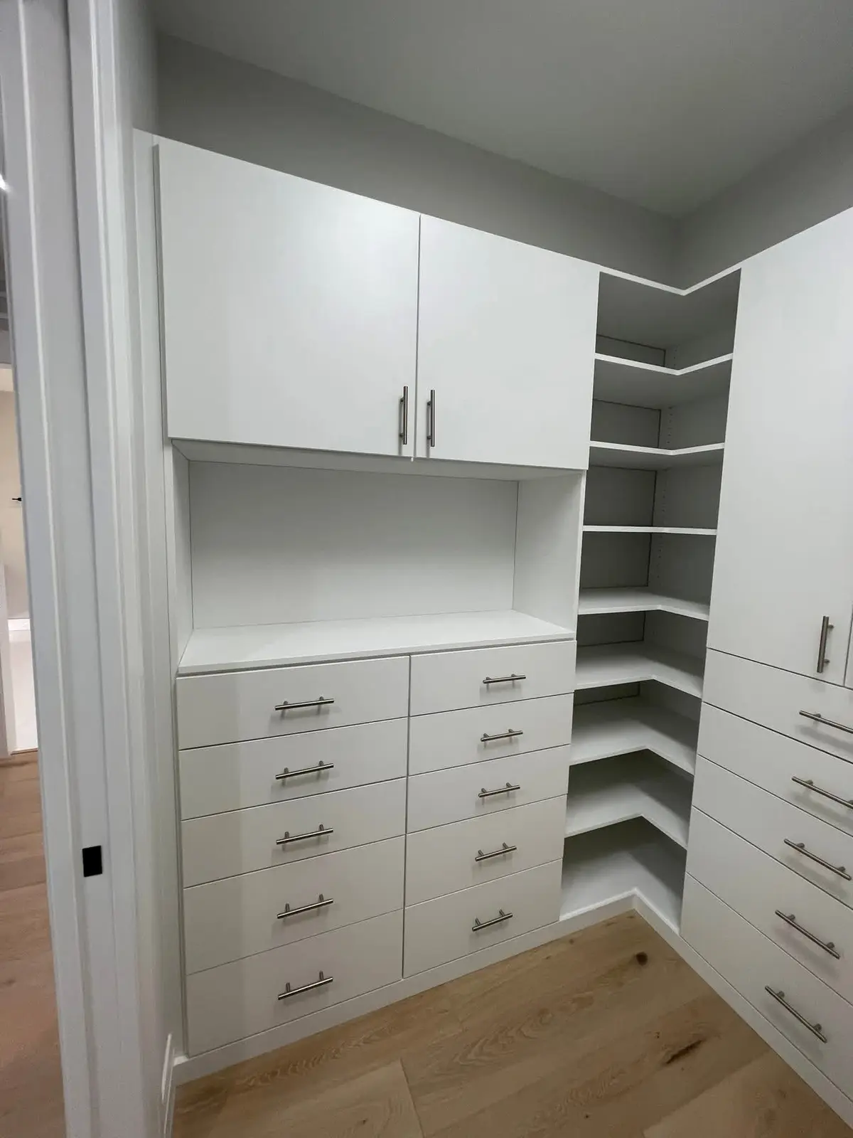 Custom white closet cabinetry with corner shelving and drawers built by C&C Multiservices in Connecticut