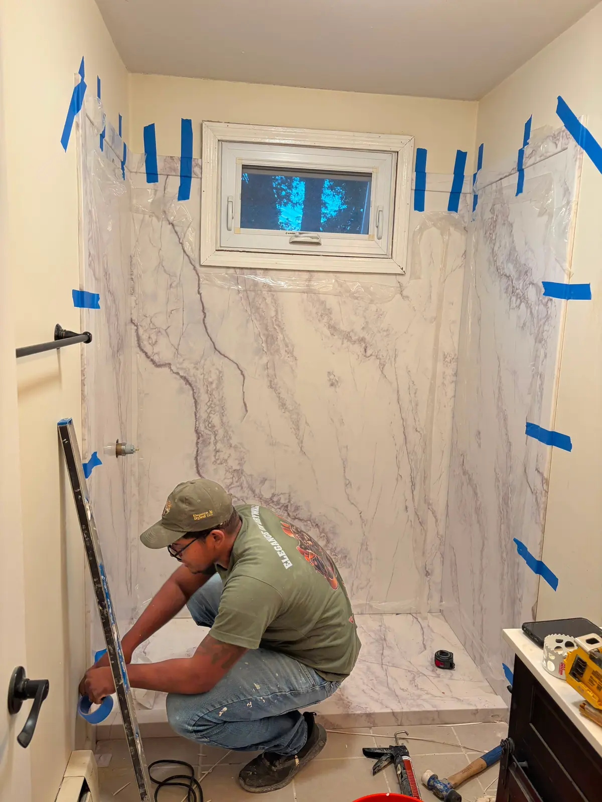 A C&C Multiservices contractor fitting a marble-look shower wall panel during a Connecticut bathroom remodel